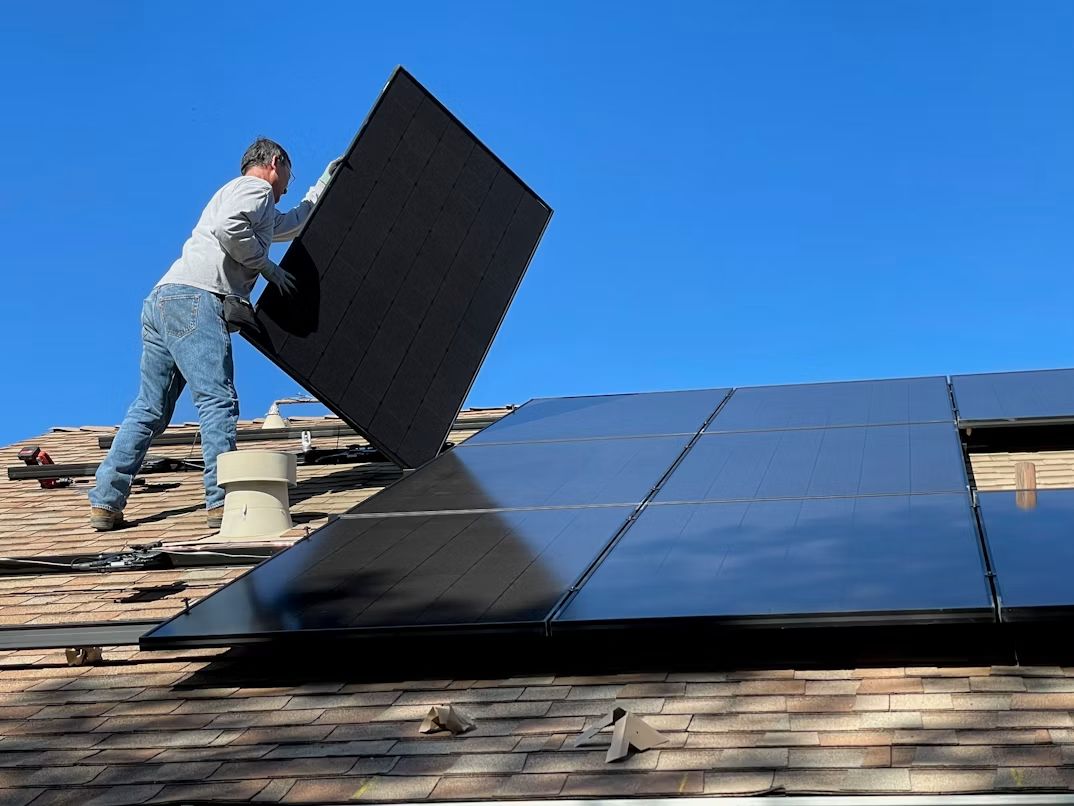 Installateur montiert ein Solarmodul auf einem Dach
